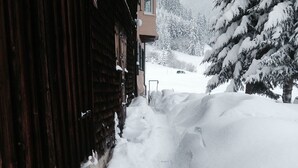 Un sendero cubierto de nieve que conduce a un edificio de madera con una ventana y una puerta visibles.