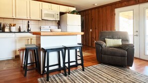 A kitchen with white cabinets, a wooden countertop, and a black bar stool.