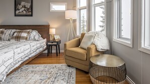 Une chambre à coucher avec un lit, une chaise, une lampe, une petite table et un tableau au mur.