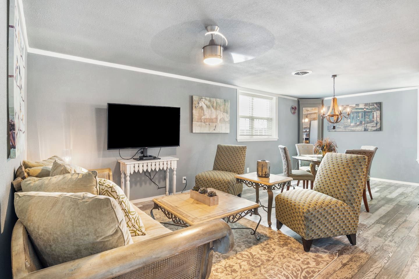 A living room with a television, patterned chairs, a coffee table, and artwork on the walls.