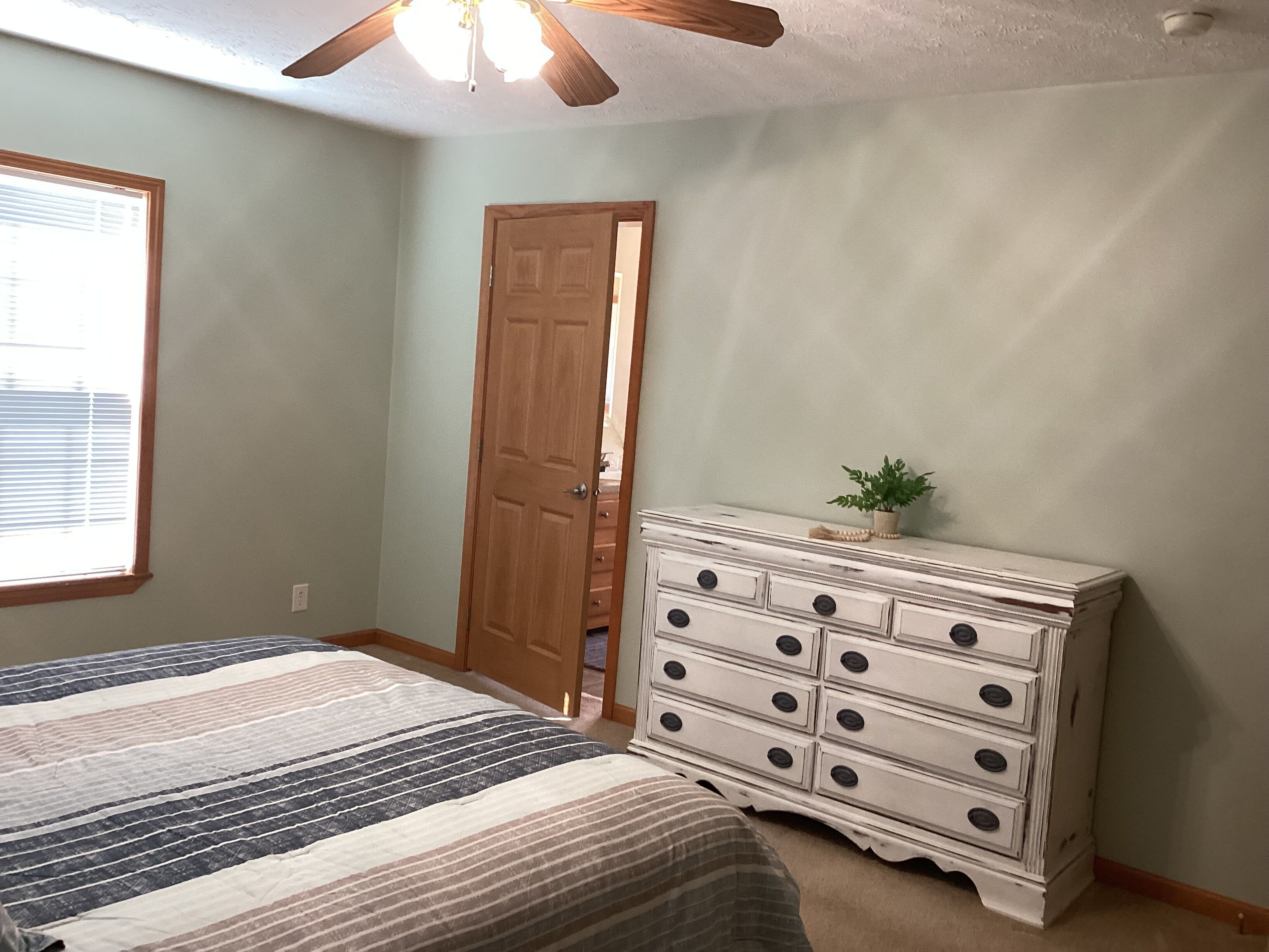 Une chambre à coucher avec un lit, une commode et un ventilateur de plafond.