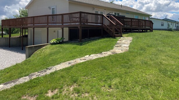 A two-story house with a wooden deck and a stone pathway leading to the entrance.