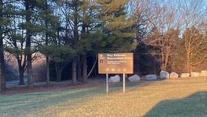 A sign in a park area indicating Ray Behrens Recreation Area, Clarence Cannon Dam, and Mark Twain Lake.