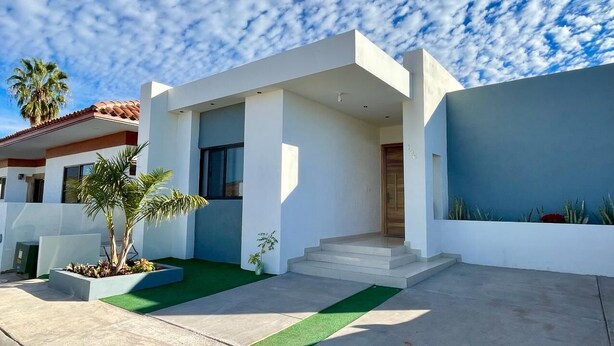 A modern two-story house with a flat roof, large windows, and a front entrance with steps. - Casa del Mural SAN Carlos (Guaymas)