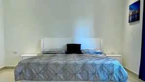 A modern bedroom with a large bed, white headboard, and a geometric patterned bedspread. - Casa del Mural SAN Carlos (Guaymas)