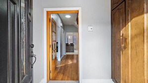 A hallway with a wooden door, a wooden cabinet, and a kitchen area in the background. - Luxurious House Big Terrace | Sleeps 16 | 3bath (Montréal)