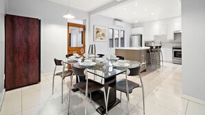 A modern kitchen with white cabinets, stainless steel appliances, and a dining area with a glass table and chairs. - Luxurious House Big Terrace | Sleeps 16 | 3bath (Montréal)