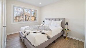 Un dormitorio con cama, ventana, mesita de noche y lámpara.