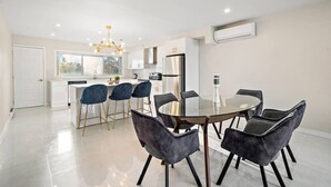 Una cocina moderna con armarios blancos, un refrigerador de acero inoxidable y una mesa de vidrio con seis sillas.