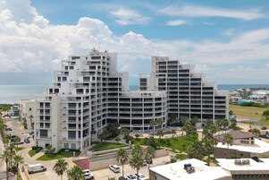 Un hotel de varios pisos con un diseño arquitectónico moderno, que cuenta con balcones y una zona de piscina.