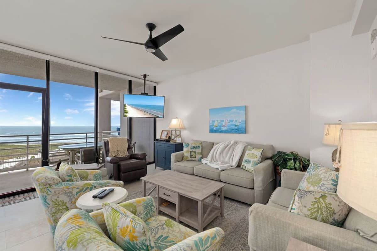 A modern living room with a sofa set, a coffee table, a TV, and a ceiling fan.