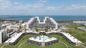 A modern hotel with a central courtyard, multiple floors, and a view of the ocean. - Sunchase IV by South Padre Resort Rental (South Padre Island)