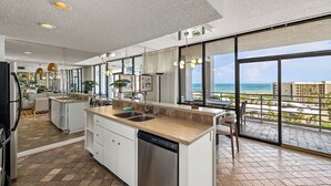 A modern kitchen with a large island, a dishwasher, and a view of the ocean. - Sunchase IV by South Padre Resort Rental (South Padre Island)