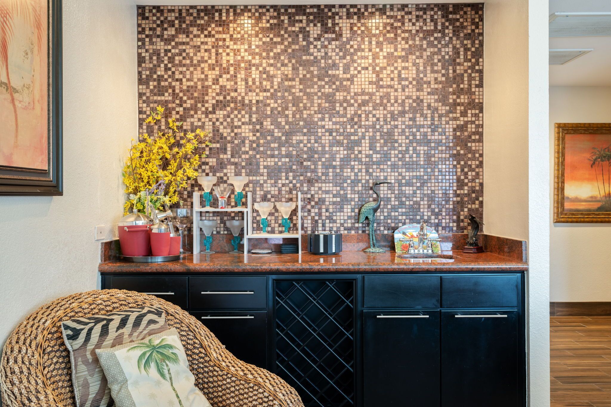 A kitchen with a mosaic backsplash, a wicker chair, and a wine cooler.