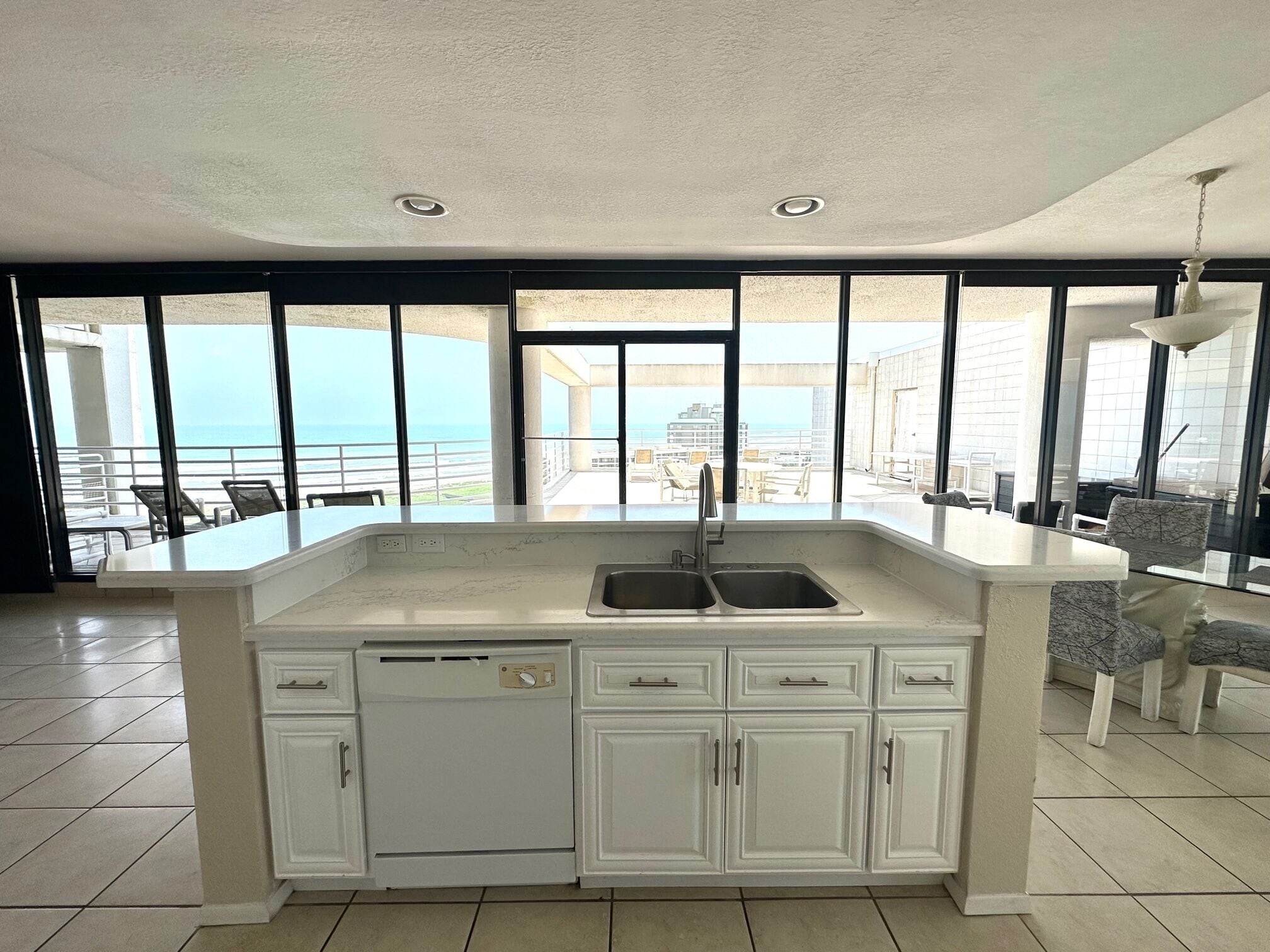 Een keuken met een groot eiland, witte kasten en uitzicht op de oceaan.