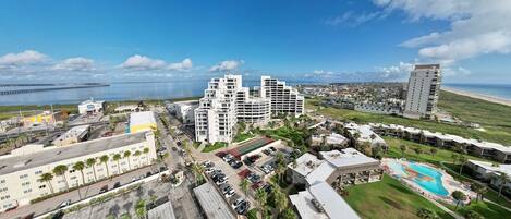 A coastal hotel complex with multiple buildings, a parking area, and a swimming pool.