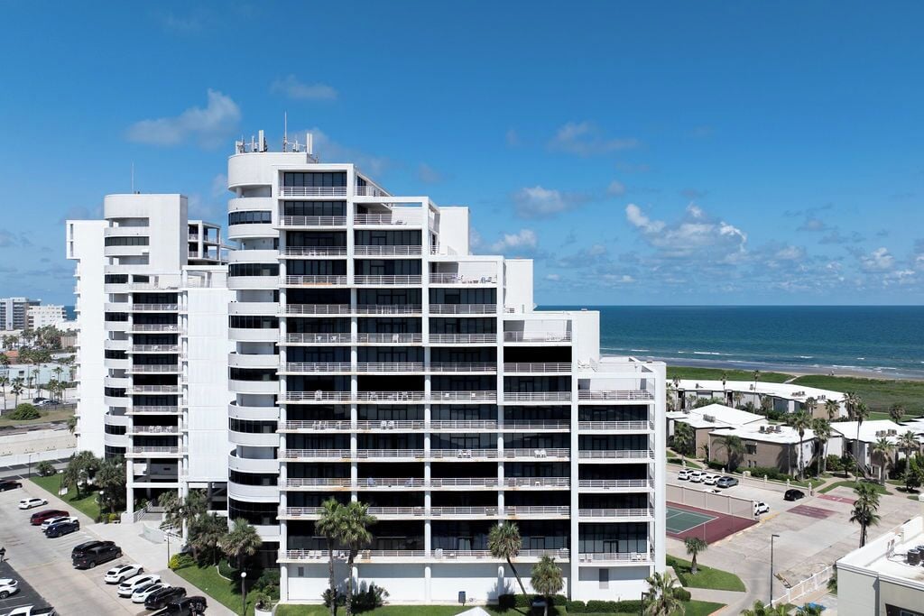 Un hotel de varios pisos con un diseño moderno, con balcones en cada planta y vista al océano.