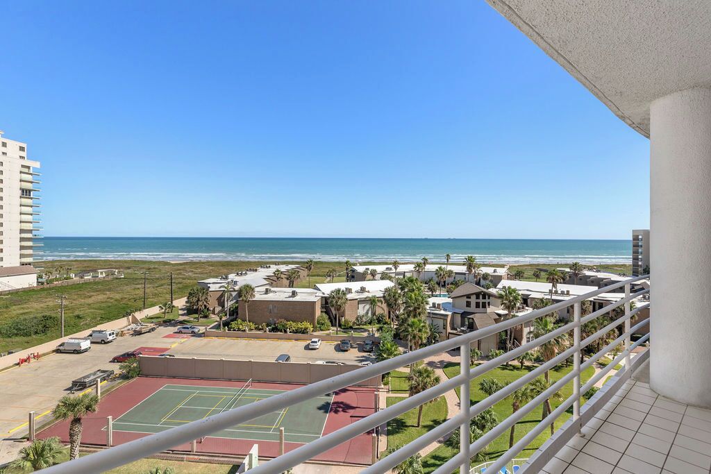 A high-rise building with a tennis court and a view of the beach.