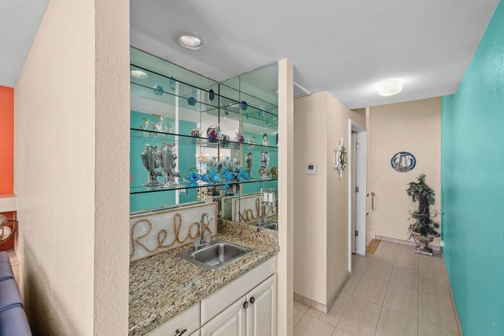 A kitchen with a glass backsplash, a sink, and cabinets.