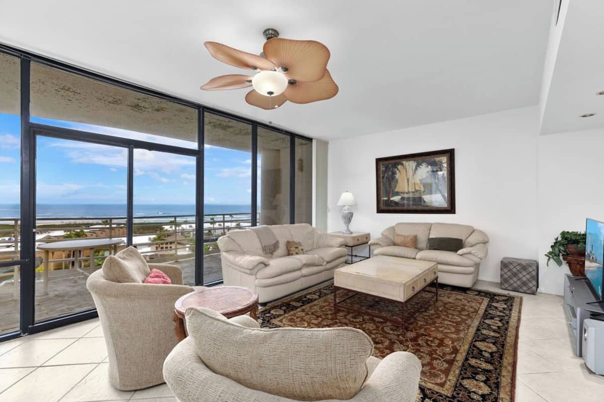 A spacious living room with a large window overlooking a scenic view, a ceiling fan, and a modern interior design.