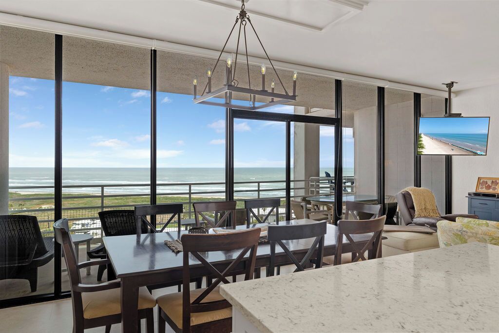 A spacious dining area with a large table and chairs, overlooking a scenic ocean view.