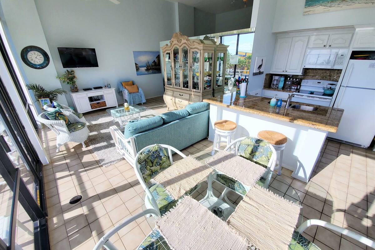 A spacious living area with a sofa, chairs, a dining table, and a kitchen with a refrigerator and microwave.