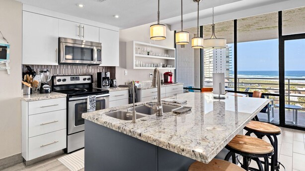 A modern kitchen with a large island, stainless steel appliances, and a view of the ocean. - Sunchase IV by South Padre Resort Rental (South Padre Island)