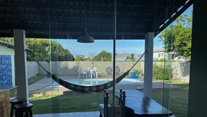 A covered patio with a hammock, a pool, and a view of the neighborhood. - Casa Familia 4 Quartos Condominio Aguas DE Sauipe (Subaúma Entre Rios)