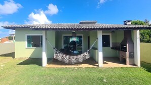 A house with a tiled roof, a hammock, and a barbecue area. - Casa Familia 4 Quartos Condominio Aguas DE Sauipe (Subaúma Entre Rios)