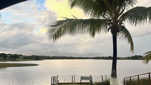 A calm lake with a palm tree and a sign labeled "PERIGO" in the foreground. - Casa Familia 4 Quartos Condominio Aguas DE Sauipe (Subaúma Entre Rios)
