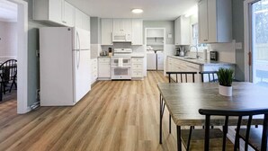Een moderne keuken met witte kasten, een houten eettafel en een plafondventilator.