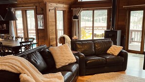 Una sala de estar acogedora con un amplio sofá de cuero negro, una mesa de comedor de madera y una chimenea.
