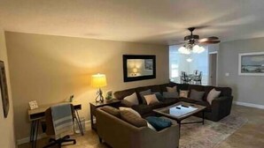 A living room with a sofa, coffee table, and a desk with a lamp.