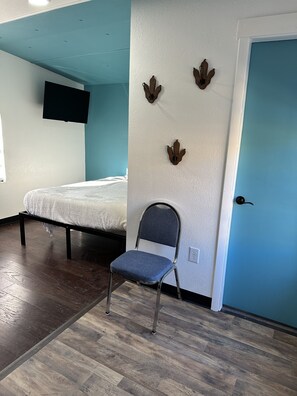 Simple, functional space with a bed, chair, and flat-screen TV.