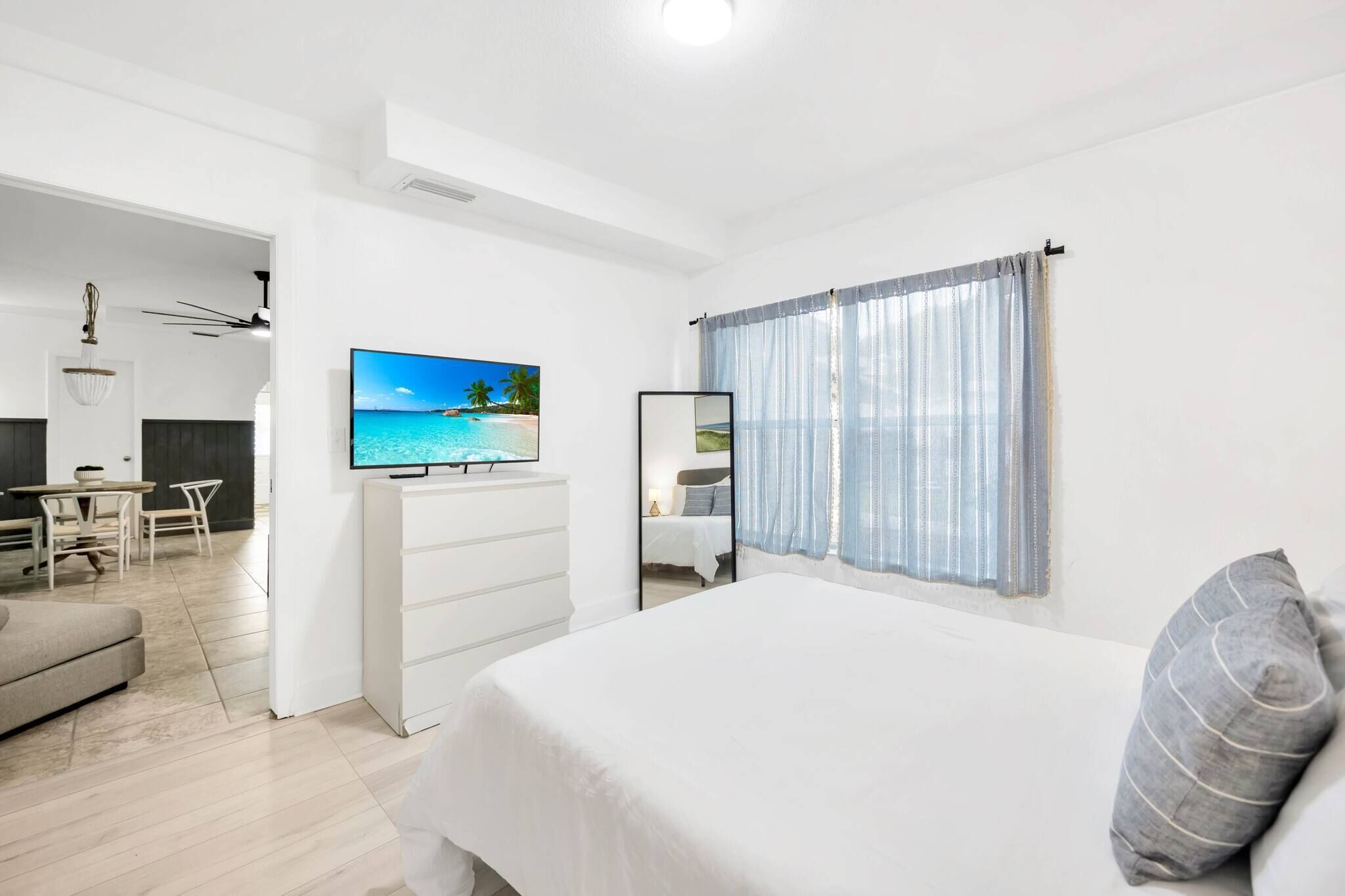 A modern bedroom with a bed, a TV, a desk, and a dining area.
