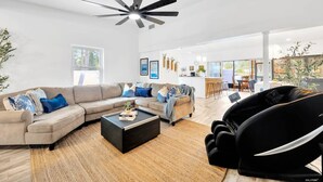 A spacious living room with a large sectional sofa, a coffee table, and a ceiling fan. There is a dining area with a bar and chairs in the background. - 2 Homes! - 4 Mn To Madeira Bch - Hottub - Htd Pool (Madeira Beach)