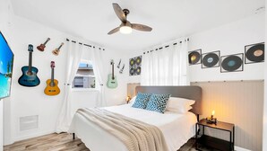 A bedroom with a bed, a ceiling fan, guitars on the wall, and framed records. - 2 Homes! - 4 Mn To Madeira Bch - Hottub - Htd Pool (Madeira Beach)