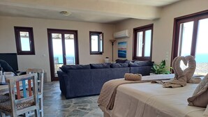 A bedroom with a bed, a sofa, a chair, and a view of the sea. - Dorothea Panoramic Villa.One of a kind, a hidden gem on the isle of Paros.Helios (Paros)