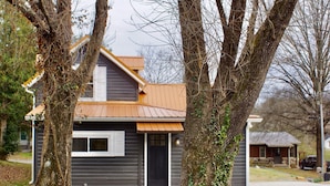 Ein modernes, zweistöckiges Haus mit dunkler Fassade, einer schwarzen Haustür und einem kleinen Fenster.