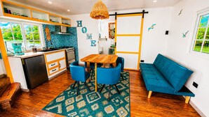 A compact kitchen with a dining area, a sofa, and a view of greenery outside. - The Sea Spot! Hip-Nautic Floating Lodge (Bocas del Toro)
