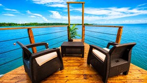 A wooden deck with wicker furniture and a view of a calm sea. - The Sea Spot! Hip-Nautic Floating Lodge (Bocas del Toro)