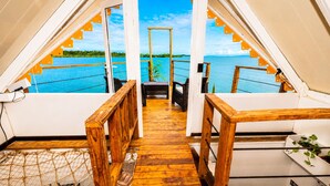 A wooden deck leading to a balcony with a view of a calm body of water and greenery. - The Sea Spot! Hip-Nautic Floating Lodge (Bocas del Toro)