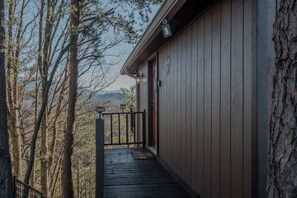 A wooden building with a porch, a door, and a view of trees and mountains.