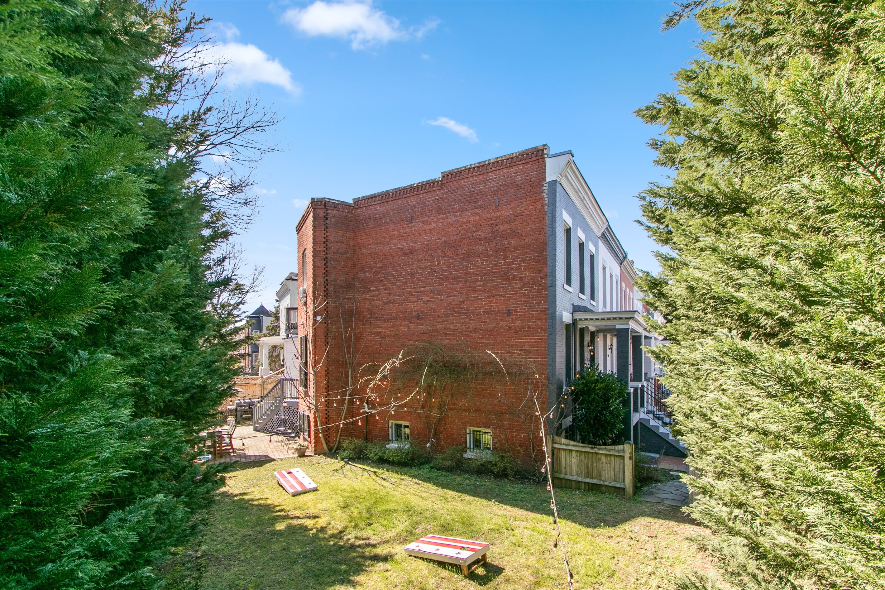 A brick building with a front porch and a small backyard with a lawn and a wooden deck.
