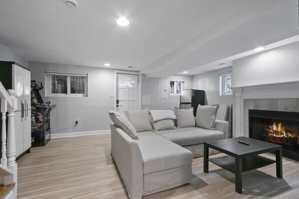 A modern living room with a sectional sofa, a fireplace, and a staircase leading to another level. - 4BR Capitol Hill Home w/ Backyard, Grill & Balcony (Washington)