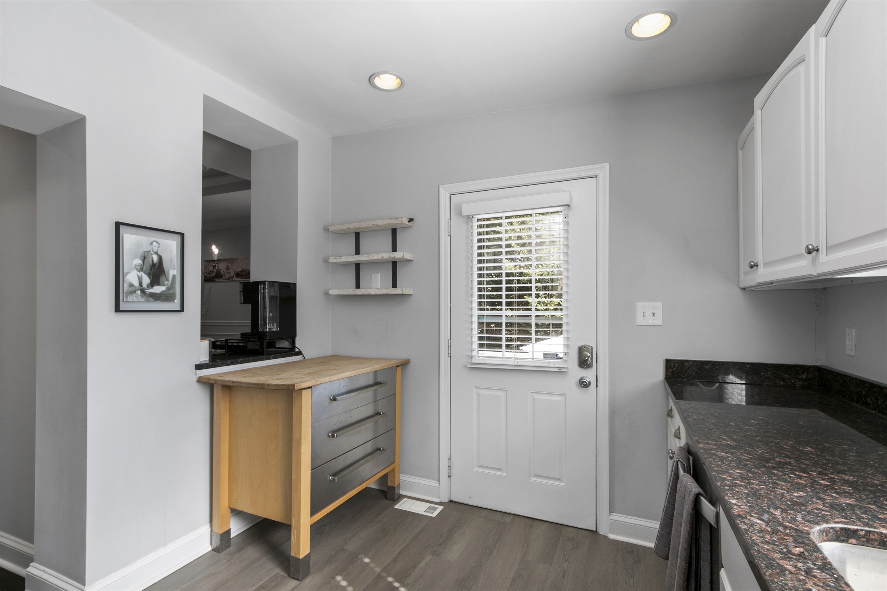 A modern kitchen with a wooden countertop, white cabinets, and a built-in stove.