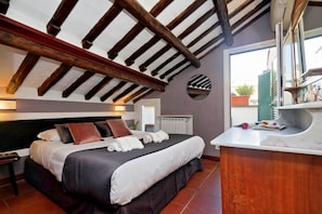 Une chambre à coucher avec un lit, un plafond en bois, une fenêtre et un meuble-lavabo dans la salle de bain.