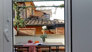 A room with a table, bench, and a view of a building with a tiled roof. - Campo de Fiori - Rome, nice apartment with terrace for 6 people (Roma)