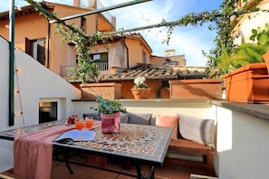 Une terrasse extérieure avec une table, des sièges et des plantes en pot.