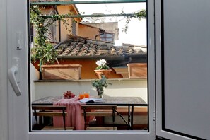 A room with a table, bench, and a view of a building with a tiled roof. - Campo de Fiori - Rome, nice apartment with terrace for 6 people (Roma)